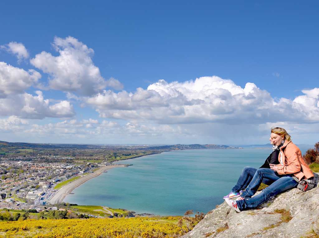 two women site on rock overlooking Bray Ireland beach